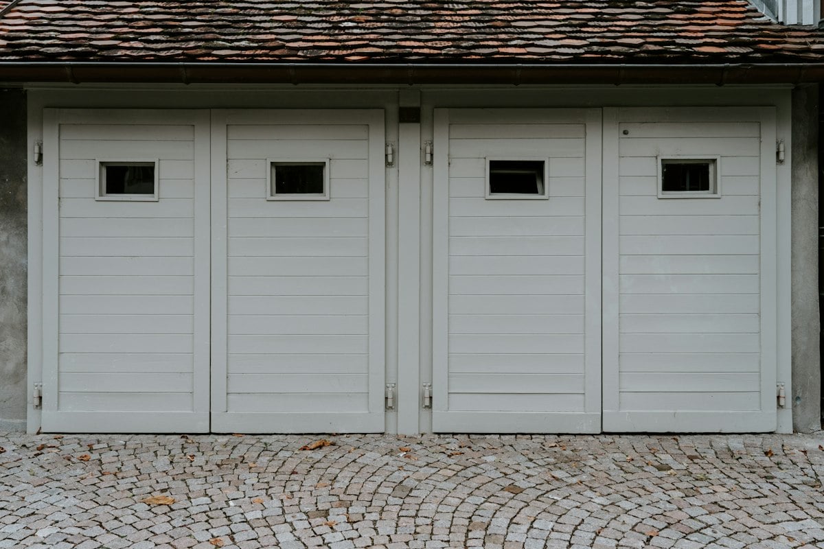 Row of white paneled garage doors with small windows